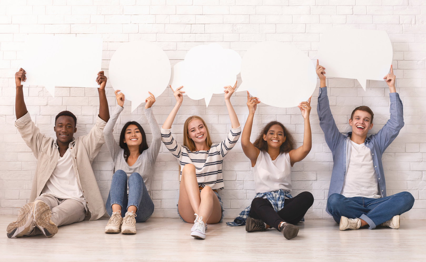 Joyful group of multiracial friends holding communication bubbles